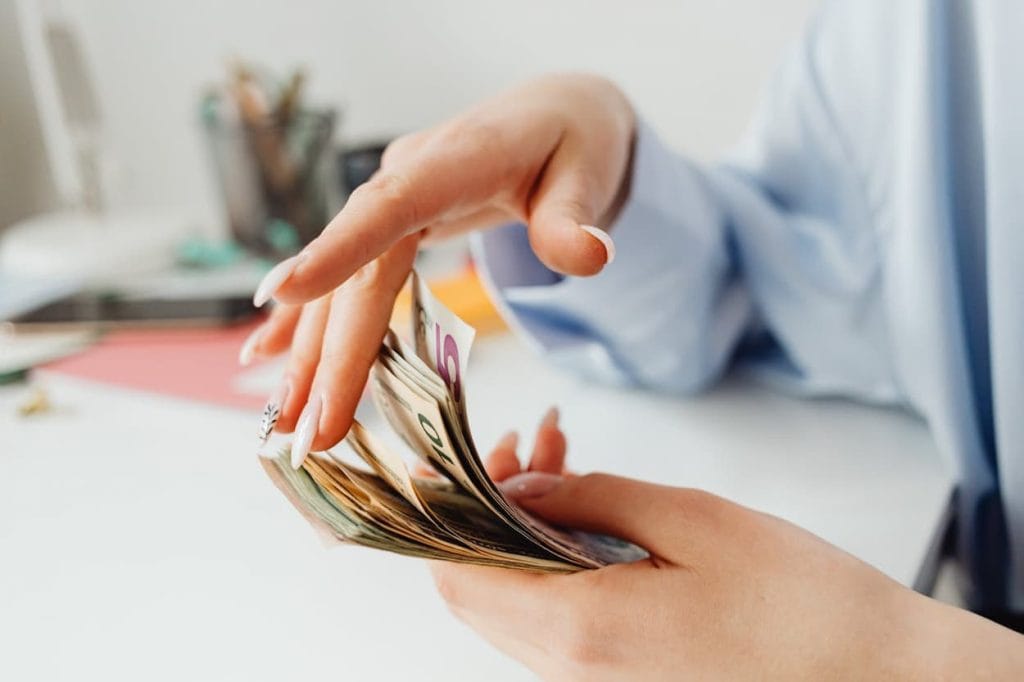 Een vrouw telt bankbiljetten aan een bureau, wat de aandacht vestigt op persoonlijke financiën en geldbeheer.