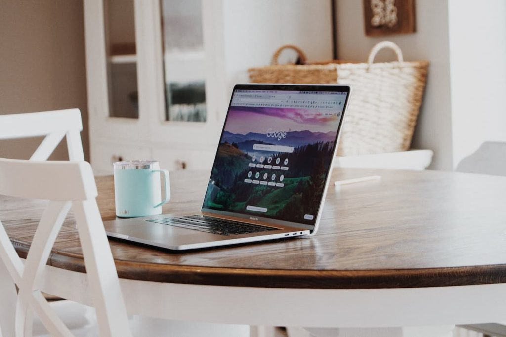 Laptop op een houten tafel met een geopend Google-scherm en een lichtblauwe mok ernaast.