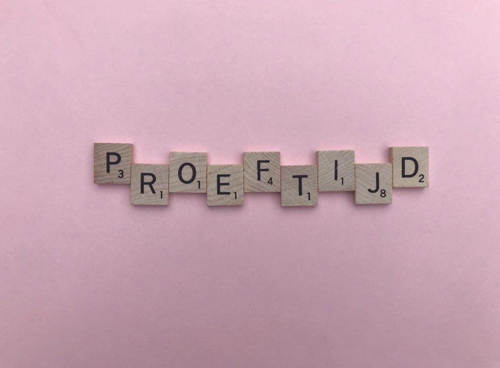 Houten scrabbleletters spellen het woord "proeftijd" op een roze achtergrond. Dit beeld kan gebruikt worden om het concept van een proefperiode of testtijd te illustreren.