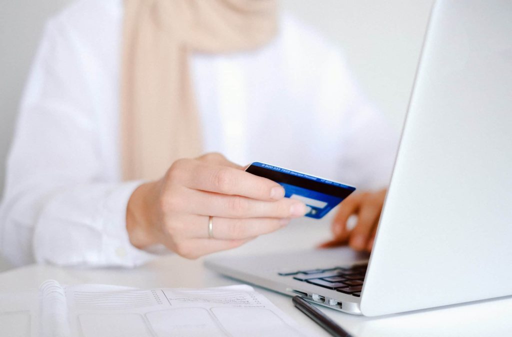 Een vrouw houdt een creditcard vast terwijl ze online winkelt op een laptop. De afbeelding benadrukt het gemak van online betalingen.